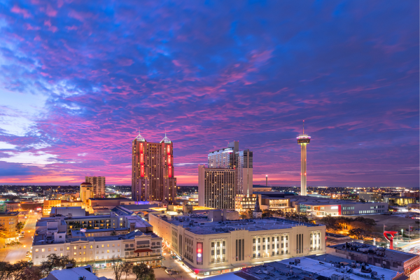 1 - Speedy Gold - Speedy Gold City skyline at sunset with a purple-pink sky, tall illuminated towers, and snow-covered streets.