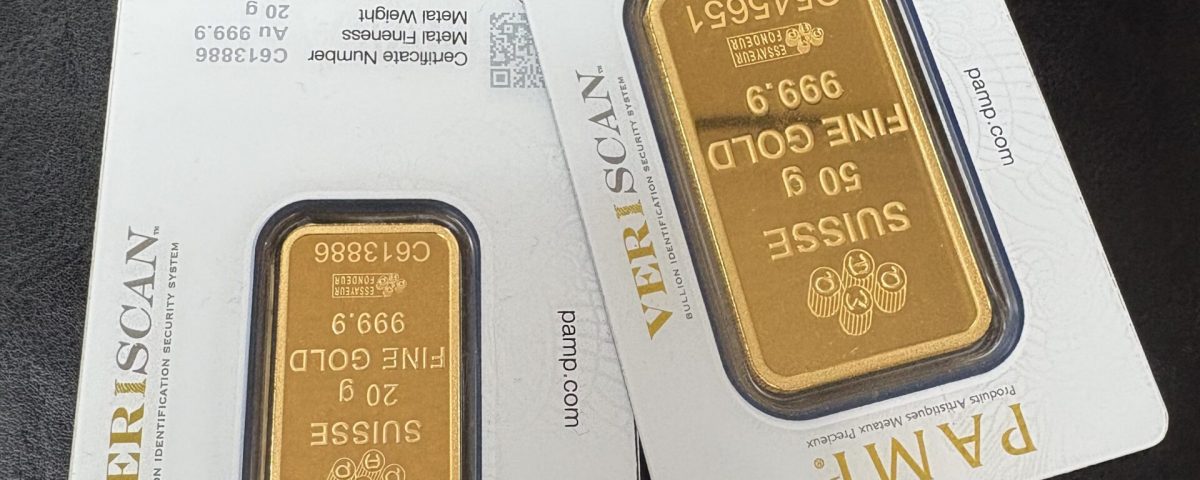 Two gold bullion bars sealed in certification cards lying on a dark leather surface.
